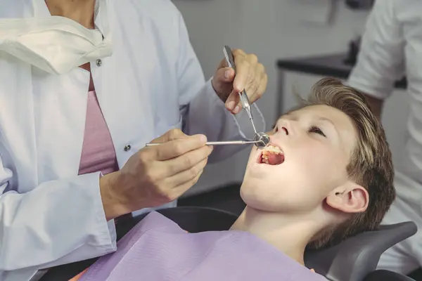Tannlege Som Undersøker Guttens Tenner Med Tannlegeinstrumenter – stockfoto