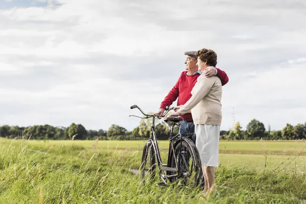Ζευγάρι Ηλικιωμένων Ποδήλατα Που Αγκαλιάζονται Αγροτικό Τοπίο — Φωτογραφία Αρχείου