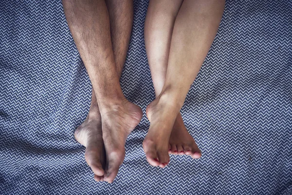 年轻夫妇赤脚腿 躺在床上的毯子 — 图库照片