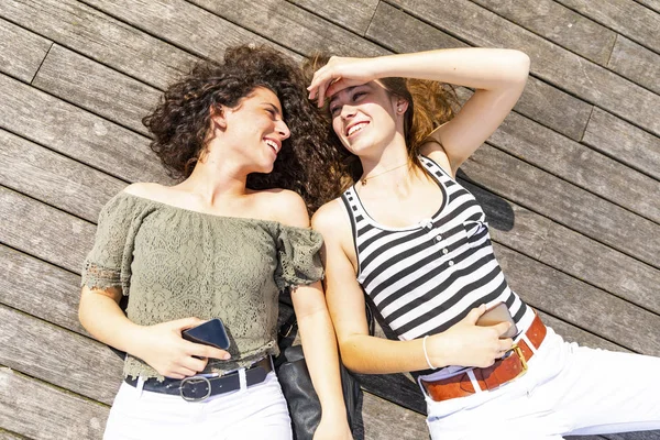 Two Happy Female Friends Lying Wooden Floor — Stock Photo, Image