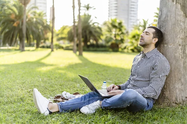 Man Met Laptop Leunend Tegen Boomstam Weide Stadspark Ontspannen — Stockfoto