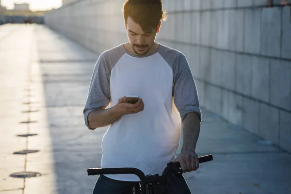 Młody Człowiek Podmiejskich Fixie Rower Patrząc Telefon Komórkowy — Zdjęcie stockowe