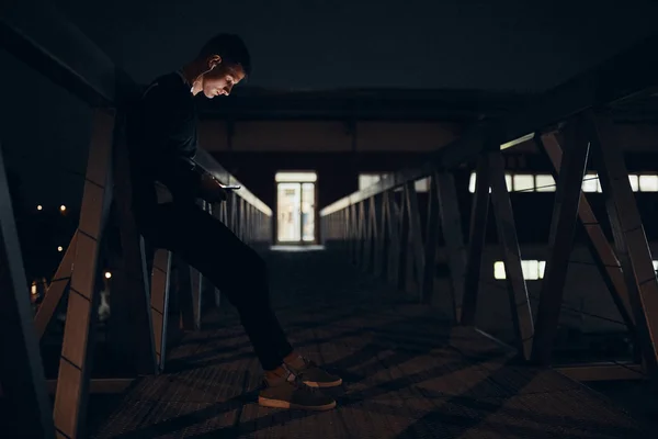 Jovem Esportivo Com Smartphone Fones Ouvido Uma Ponte Noite — Fotografia de Stock