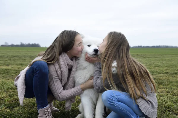 Two Girls Crouching Meadow Kissing Dog — ストック写真