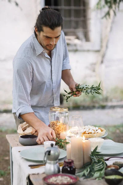 Hombre preparando una cena romántica a la luz de las velas al aire libre - foto de stock