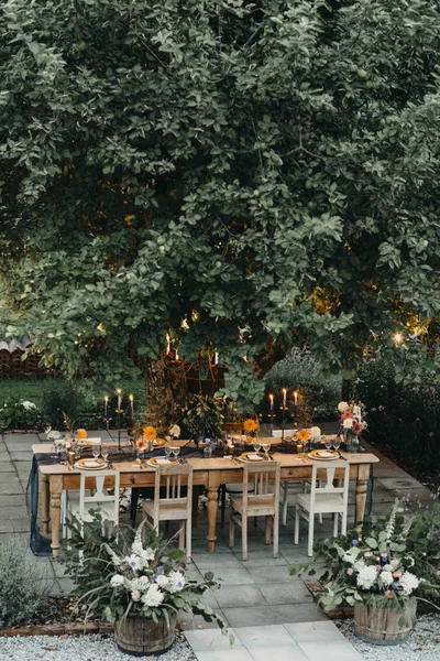 Table dressée festive avec des bougies sous un arbre — Photo de stock