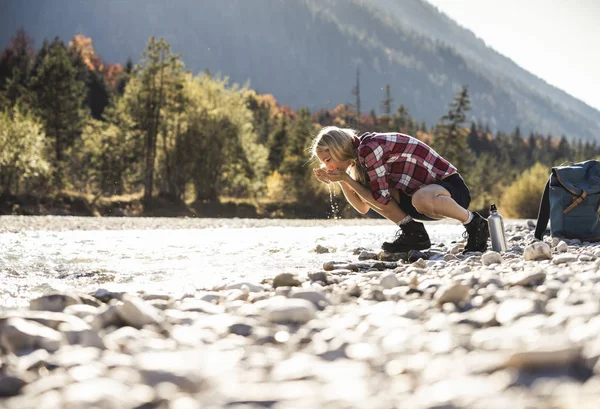 Austria, Alps, woman on a hiking trip having a break at a brook — Stock Photo