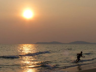 gün batımında sahilde çalışan çocuk