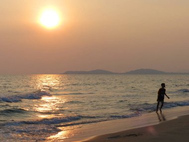 gün batımında sahilde çalışan çocuk