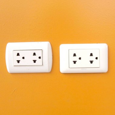 Turuncu duvara monte beyaz elektrik prizi