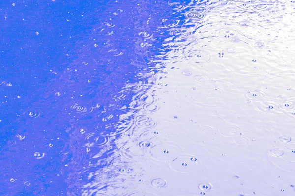 Regendruppels op het blauwe water, abstracte achtergrond — Stockfoto