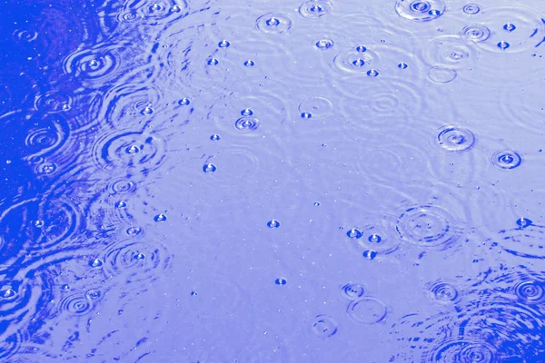 Regendruppels op het blauwe water, abstracte achtergrond — Stockfoto