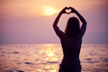 Sabah güneşi ufuk içinde el ile yapılan kalp şekli. Güzel gün batımı karşı kalp.
