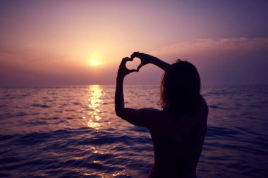 Sabah güneşi ufuk içinde el ile yapılan kalp şekli. Güzel gün batımı karşı kalp.