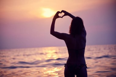 Sabah güneşi ufuk içinde el ile yapılan kalp şekli. Güzel gün batımı karşı kalp.