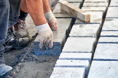 Bir işçi 's eldivenli elleri çekiç taş döşeme eklemenizi sağlar. İşçi kaldırım Arnavut kaldırımı taşları ve granit taşlar kullanarak oluşturma.