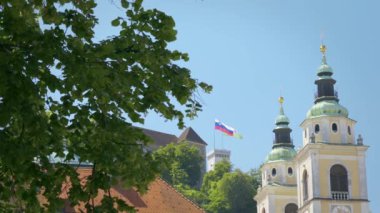 Ljubljana Kalesi sıcak bir yaz gününde 4k arka planda Ljubljana Kalesi ve ön planda kilise Katedrali.