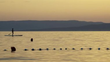 Sessiz denizde kürek yatılı ayağa kalk, yaz gün batımı