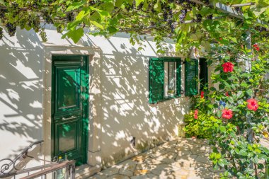 Yunanistan - Corfu - Barbati - 1 Ağustos 2018: Üzüm bitkiler ile bir pergola ev.