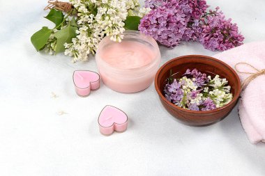 Tahta bir kâse ve vücut kremi, cilt ve vücut bakımı, aromaterapi, yaşam tarzı konsepti, sunum ve davetiye için tebrik kartı, leylak çiçeklerinden gelen hoş kokulu su içeren spa malzemeleri.