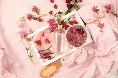 Kaplıca ve sağlık kompozisyonu, ahşap bir kasede pembe çiçek kokulu su, gül suyu ve vücut kremi ve cilt ve vücut bakımı ile aroma terapisi, düzlük.,