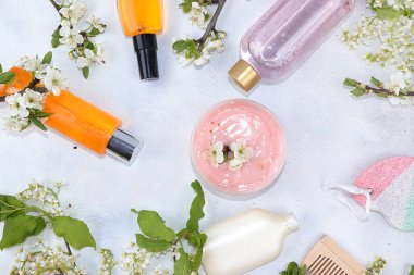 Spa malzemeleri, kozmetik yağlar ve cilt ve vücut bakımı için kremler. Gri arka planda çiçek açan kiraz dallarıyla birlikte. Alışveriş konsepti ve modern kadın, satış, seçici odak