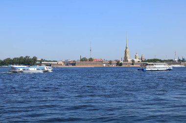 Rusya, Petersburg, 8 Haziran 2019. Vasilyevsky Adası 'nın tükürüğü. Fotoğrafta Neva kıyısındaki Peter ve Paul Kalesi gökyüzüne karşı ve şehir manzarasına hayran turistlerle dolu bir eğlence teknesi..