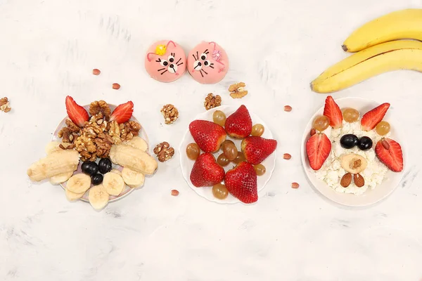 Strawberry yogurt, granola, cottage cheese, fresh berries, apples, strawberries and grapes on a light table. The concept of healthy and natural food. Useful breakfast, food for children, selective focus, top view
