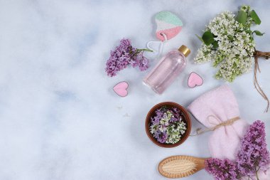 Ahşap bir kasedeki leylak çiçeklerinin hoş kokulu suyuyla spa ve sağlık kompozisyonu gül suyu, vücut kremi ve cilt bakımı ile aroma terapisi.,