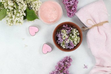 Ahşap bir kase ve banyo havlusunda kokulu leylak çiçekleri olan spa malzemeleri, aromaterapi ve cilt bakımı, düzlük, yaşam tarzı konsepti