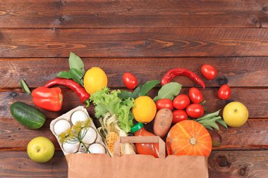 Karanlık bir arka planda kağıt poşet içindeki doğal ürünler, süpermarketten alışveriş konsepti, yiyecek teslimatı, bağışlar. Sebze, meyve, yumurta.,