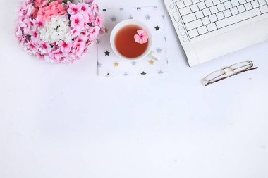 Modern bir kadının çalışma masası, ev ofisi. Not defteri, çay, ışık masasındaki bahar çiçekleri. Asgari iş konsepti, düz konum, metin için yer.