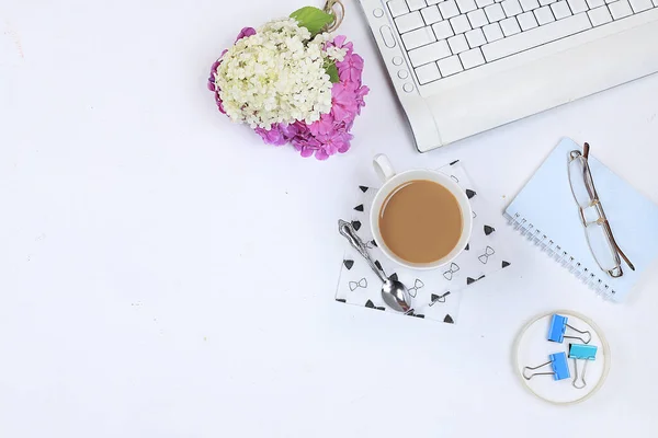 Modern woman desktop, home office. Computer, flowers and a cup of coffee on a sunny table. lifestyle concept, flat lay, place for text