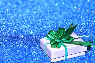 Noel ya da yeni yıl arkaplanında mavi ışık ve seçici odak noktası olan hediye kutusu var. Mutlu bir kutlamanın hazırlığı, neşeli bir atmosfer.