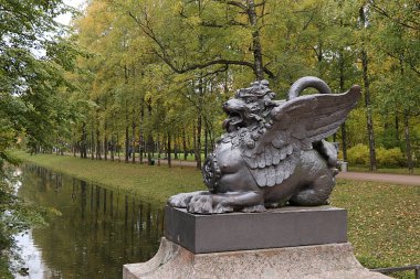 Rusya, St. Petersburg, 28 Eylül 2019, Alexander Park. Fotoğrafta, Tsarskoye Selo 'daki Ejderha Köprüsü' nde bir ejderha heykeli bir sonbahar parkının arka planına karşı.