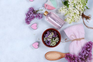 Koyu bir zemin, aromaterapi, cilt ve vücut bakımı, yassı yaşam tarzı konsepti ve modern kadın üzerinde ahşap bir kasede bulunan leylak çiçeklerinin hoş kokulu suyuyla spa ve sağlık kompozisyonu.