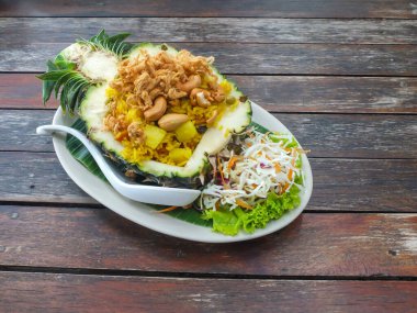 Tahta bir masada ananasla servis edilen Tayland usulü kızarmış pilav..