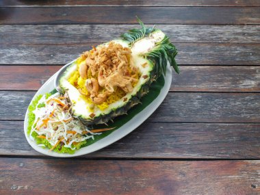 Tahta bir masada ananasla servis edilen Tayland usulü kızarmış pilav..