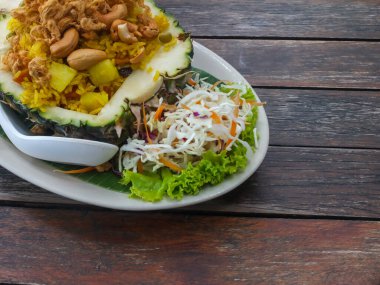 Tahta bir masada ananasla servis edilen Tayland usulü kızarmış pilav..