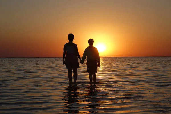 Zwei Personen Gehen Bei Sonnenuntergang Auf Dem Wasser — Stockfoto