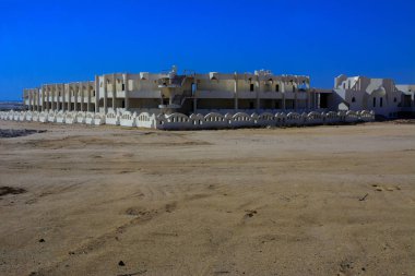 Sharm el-Sheikh, Mısır - 14 Mart 2018. Parçaları bir bitmemiş İnşaat ve Kızıldeniz sarı kum ve mavi gökyüzü arka plan üzerinde terk edilmiş bir otel. Geri kalanı üzerinde bir yaz günü açık havada seyahat.