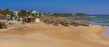 Sharm el-Sheikh, Mısır - 14 Mart 2018. Bir dizi karşı bir mavi gökyüzü ve mavi deniz kumlu bir plaj üzerinde aşırı ısınma karşı korumak için hasır şemsiyeler. Yaz tatil, turizm, seyahat kavramı.