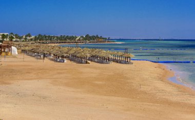 Sharm el-Sheikh, Mısır - 14 Mart 2018. Bir dizi karşı bir mavi gökyüzü ve mavi deniz kumlu bir plaj üzerinde aşırı ısınma karşı korumak için hasır şemsiyeler. Yaz tatil, turizm, seyahat kavramı.