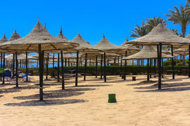 Sharm el-Sheikh, Mısır - 14 Mart 2018. Bir dizi karşı bir mavi gökyüzü ve mavi deniz kumlu bir plaj üzerinde aşırı ısınma karşı korumak için hasır şemsiyeler. Yaz tatil, turizm, seyahat kavramı.
