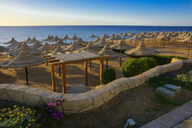 Sharm el-Sheikh, Mısır - 14 Mart 2018. Bir dizi karşı bir mavi gökyüzü ve mavi deniz kumlu bir plaj üzerinde aşırı ısınma karşı korumak için hasır şemsiyeler. Yaz tatil, turizm, seyahat kavramı.