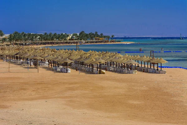 Sharm el-Sheikh, Mısır - 14 Mart 2018. Bir dizi karşı bir mavi gökyüzü ve mavi deniz kumlu bir plaj üzerinde aşırı ısınma karşı korumak için hasır şemsiyeler. Yaz tatil, turizm, seyahat kavramı.