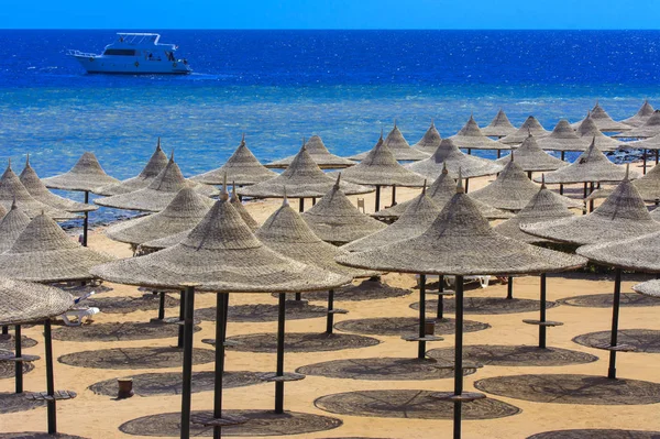 Sharm el-Sheikh, Mısır - 14 Mart 2018. Bir dizi karşı bir mavi gökyüzü ve mavi deniz kumlu bir plaj üzerinde aşırı ısınma karşı korumak için hasır şemsiyeler. Yaz tatil, turizm, seyahat kavramı.