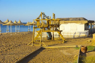 Çocuk ahşap oyun grupları boş bir sahil sarı kum ve mavi gökyüzünün bir arka plan üzerinde terk edilmiş. Atılmış, gereksiz şeyler. Tatil, turizm.