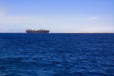 Bir büyük yük gemisi nakliye konteyner ve açık denizde mavi gökyüzüne karşı toplu yükleri için. İş lojistik ve taşımacılık uluslararası bir geminin açık denizlerde.