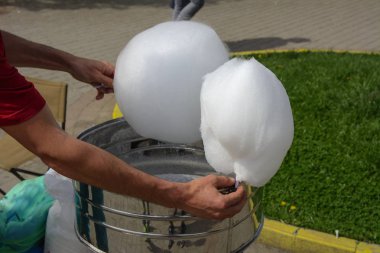 Makine tatlı yün, üretim yapmak için. Tatlı Beyaz Pamuk yün bir park arka plan karşı elinde bir sopa